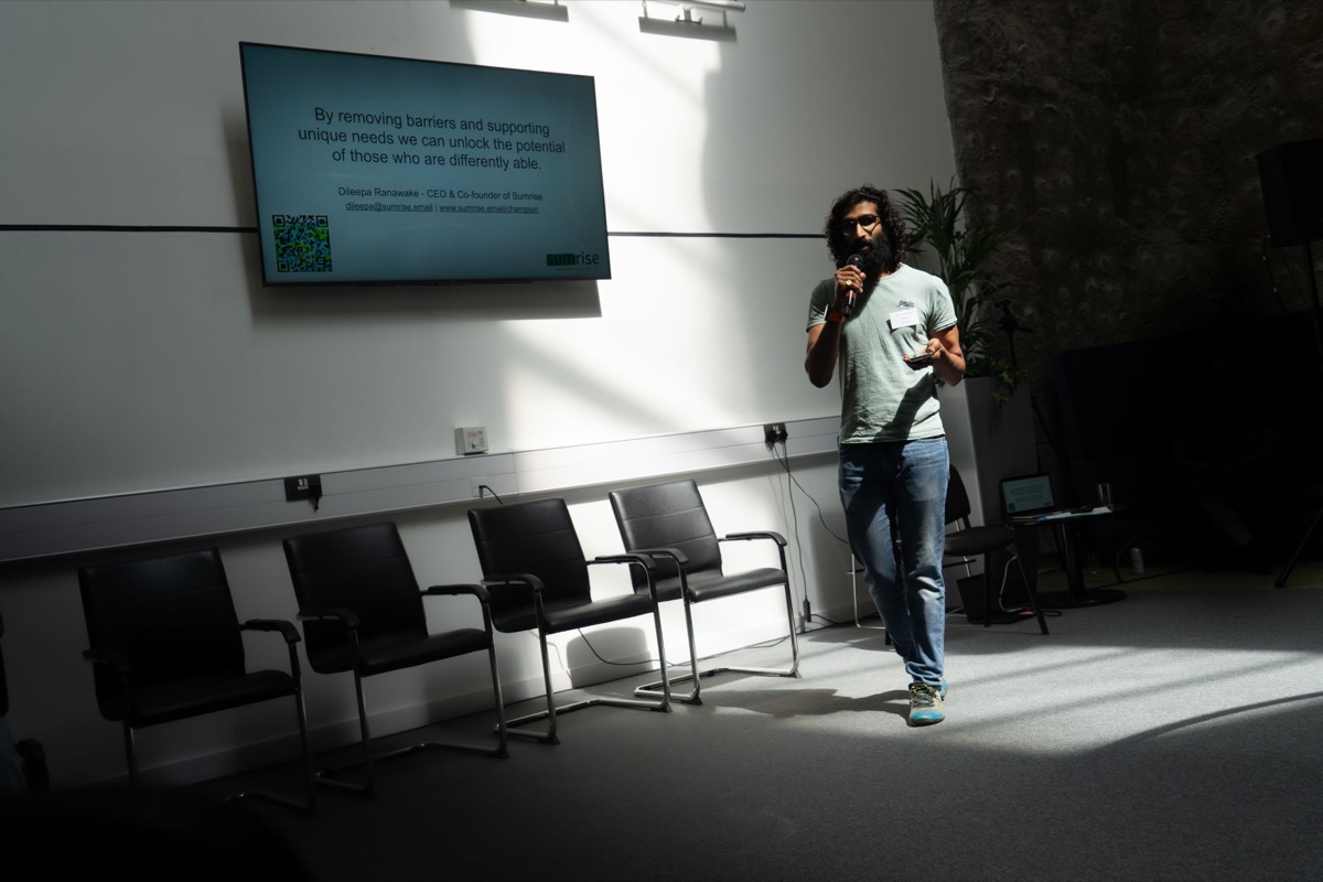 Dileepa speaking at the University of Warwick, in front of his slide about removing barriers